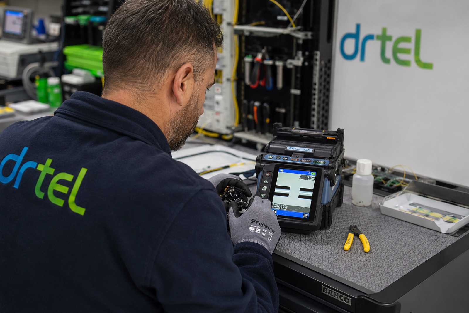 Técnico de DRTEL realizando fusión de fibra óptica con soldadora automática.